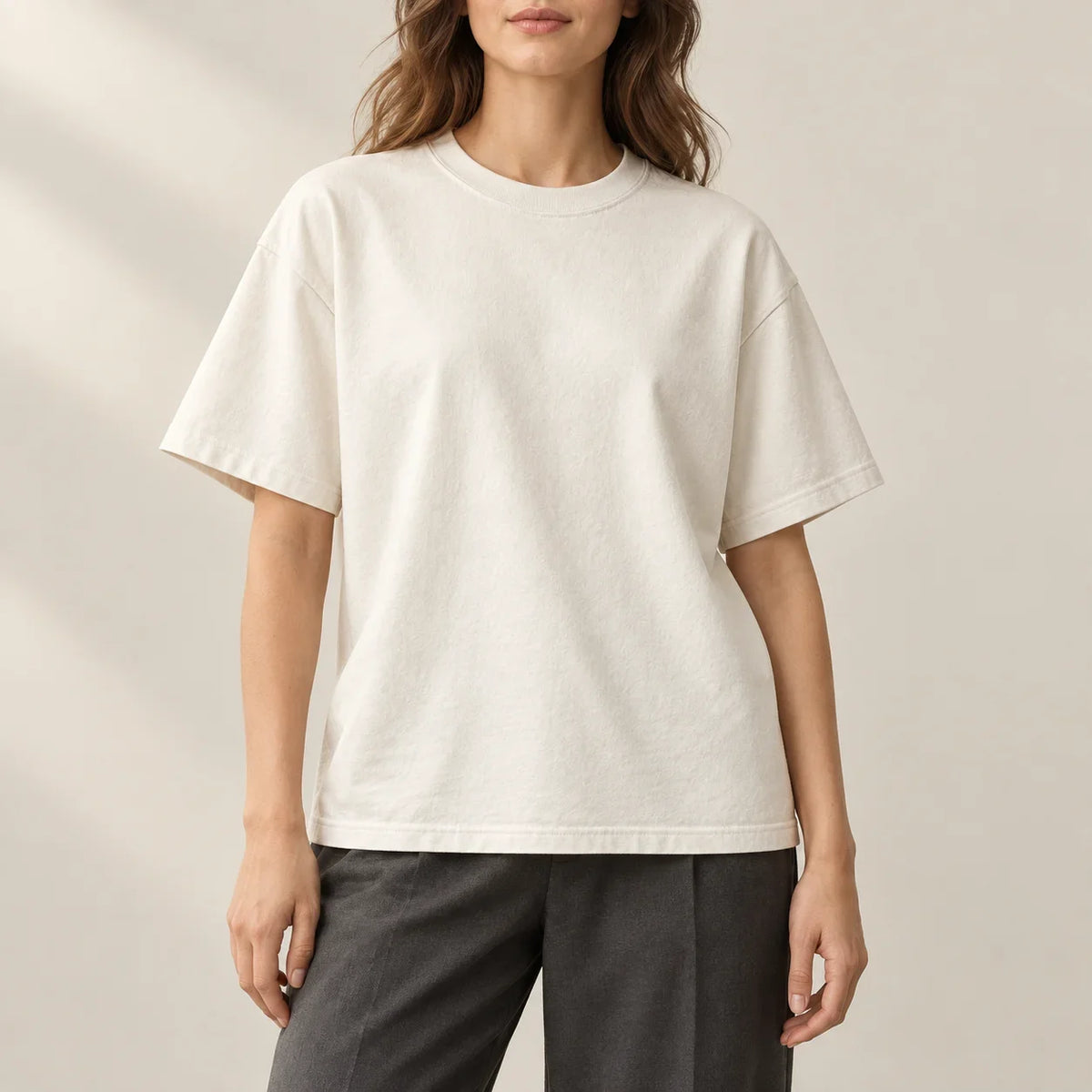 Relaxed ivory T-shirt worn with charcoal trousers